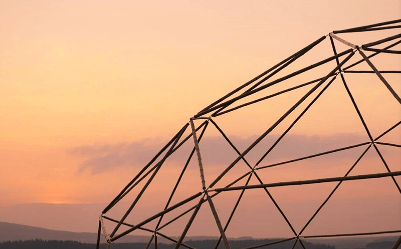 A moso bamboo geometric dome made by Atlas Domes at sunset